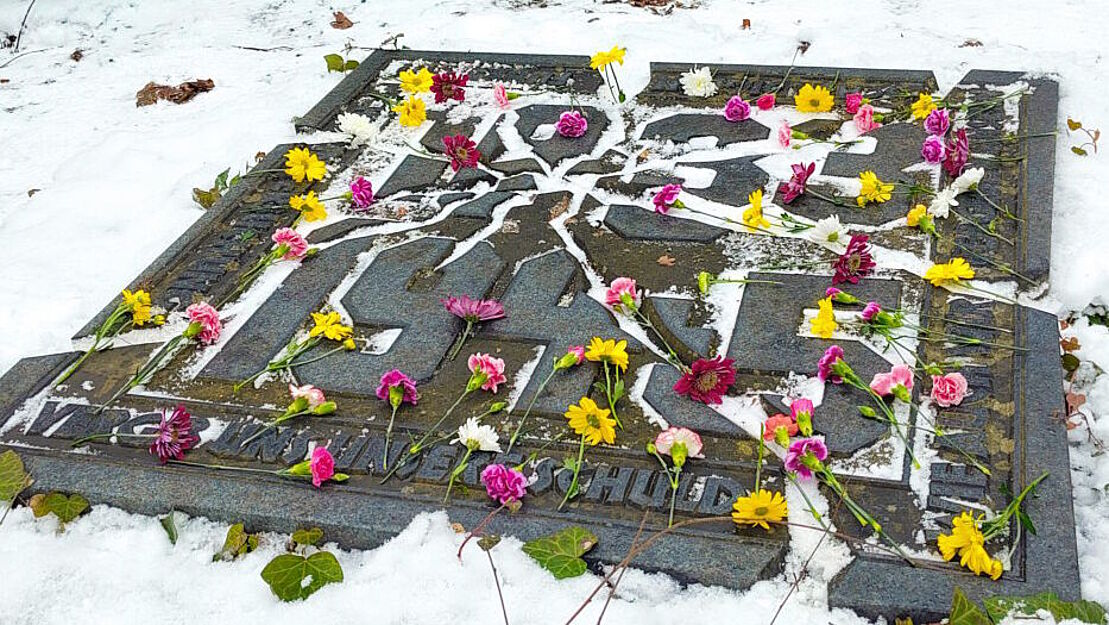 Ansicht des Gedenksteins mit zuvor dort abgelegten Blumen