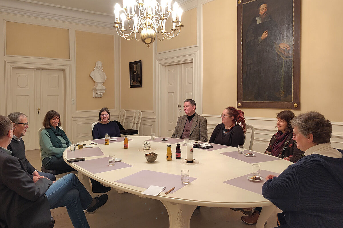 Acht Personen um einen großen Sitzungstisch - Lars-Christian Koch in der Mitte